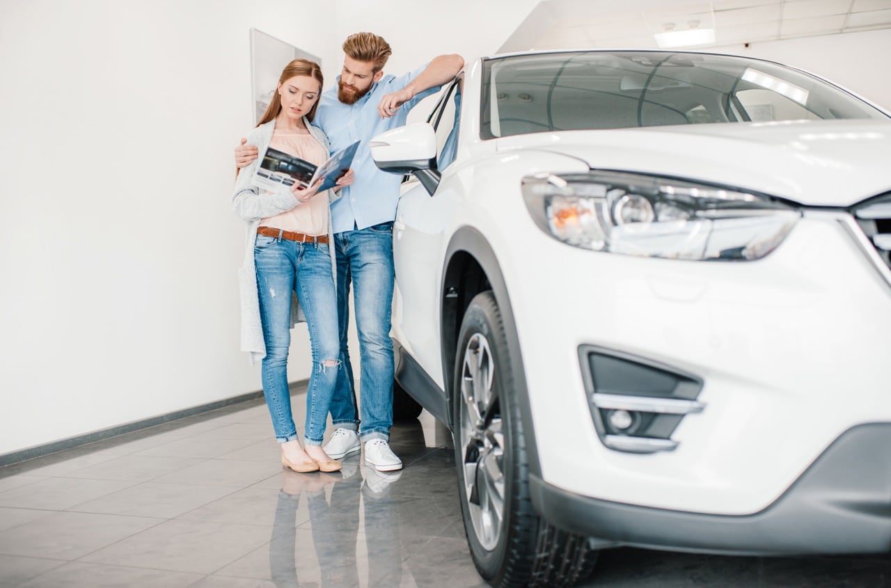 Un couple analysant attentivement différentes offres de leasing automobile pour faire le choix le plus adapté à leurs besoins