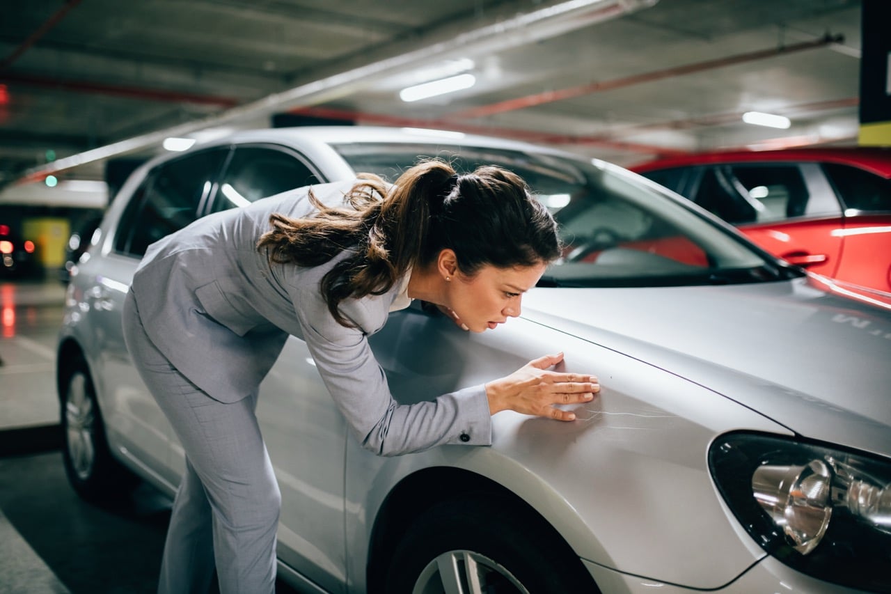 Une femme qui constate les dégats de son véhicule assuré au tiers